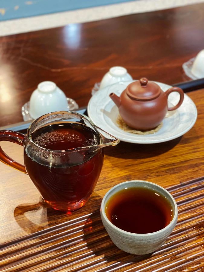 Hình ảnh mô tả nghệ thuật thưởng trà Phổ Nhĩ trong trà đạo, thể hiện thao tác rửa trà, rót trà và cảm nhận màu nước, hương thơm, khẩu cảm trầm dày đặc trưng của trà Phổ Nhĩ Vân Nam.